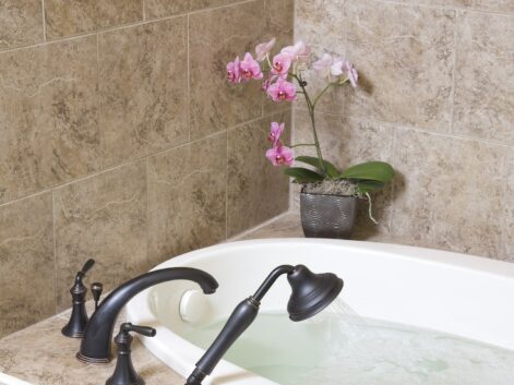 large bathtub filled with water with a pink orchid on the side